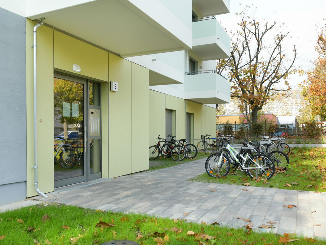 Außenansicht degewo-Neubau Tramper Weg 6: Eingangsbereich mit Rasenflächen und Fahrradständern.