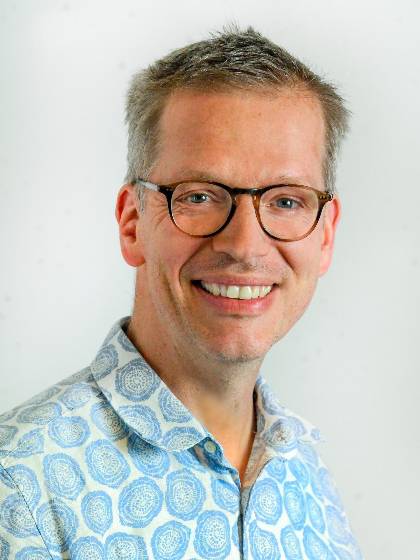 Porträt eines Beiratsmitglieds Stefan Wallentin mit Brille und gemustertem Hemd vor hellem Hintergrund.