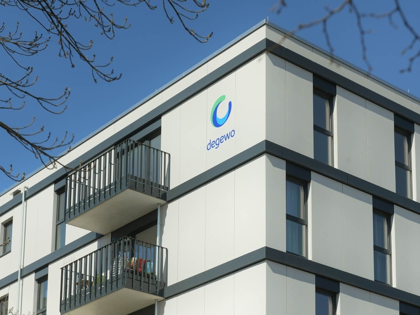 Außenansicht Eckfassade degewo-Neubau Ludwig-Renn-Straße 56 bis 64 mit degewo-Logo.