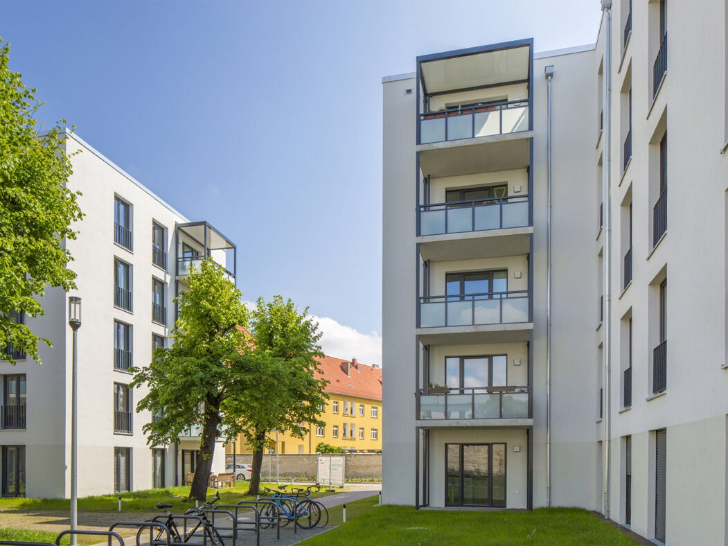Außenansicht degewo-Neubau Luisenstraße 26 bis 26 A: Hofseite mit Bäumen, Grünflächen, Wegen und Fahrradständern.