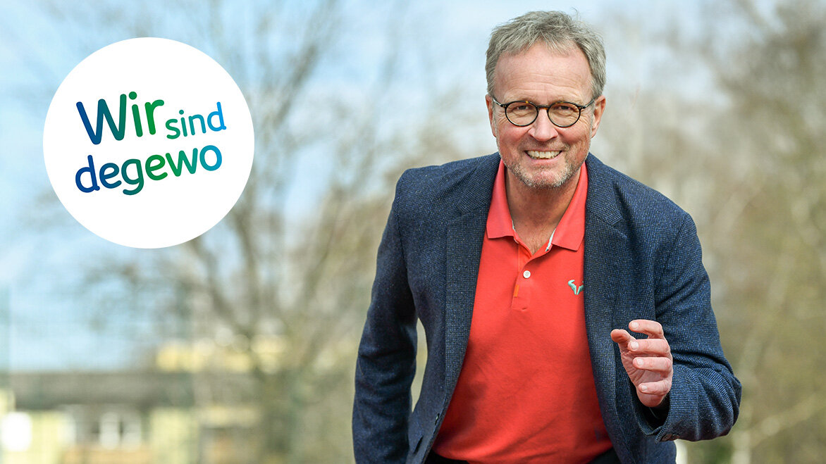 Ein Mann sprintet zur Kamera hin. Er lächelt in die Kamera, im Hintergrund sind verschwommen Bäume zu sehen.