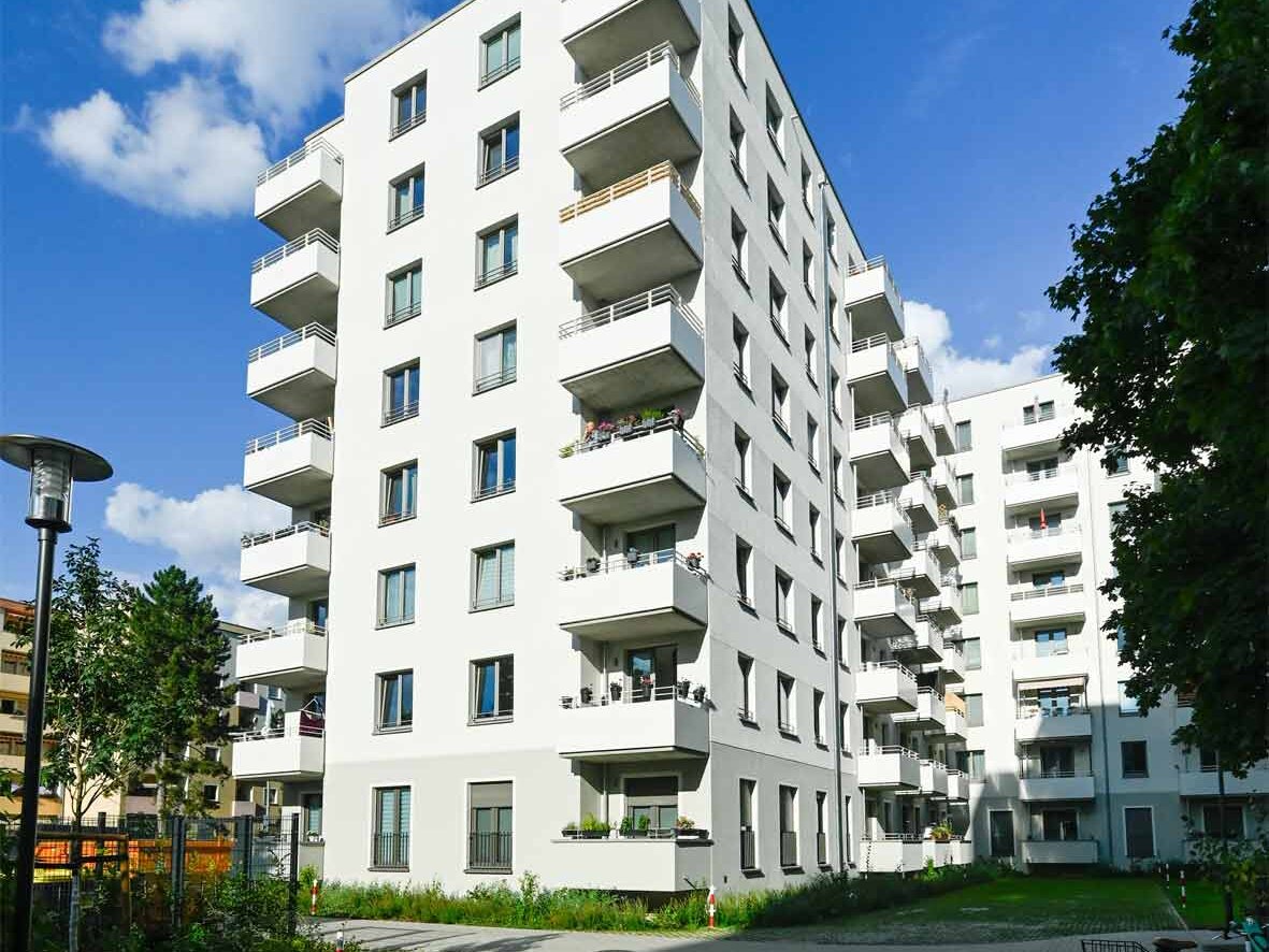 Außenansicht degewo-Neubau Borgenhagenweg 43A mit Straßenlaterne links, Weg und Fahrrad rechts im Vordergrund.