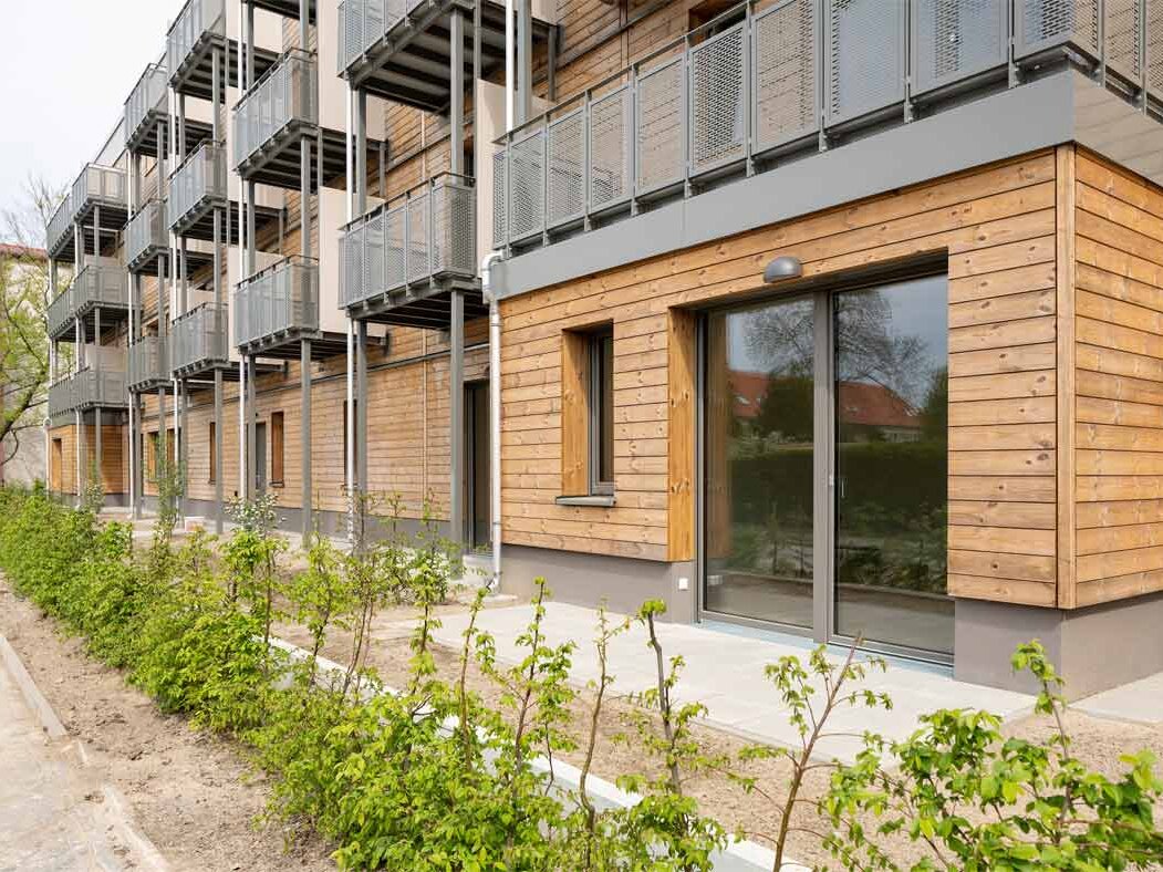 Außenansicht degewo-Neubau Beyrodtstraße 52: Fassade mit Balkonen sowie Beeten mit Sträuchern im Vordergrund.