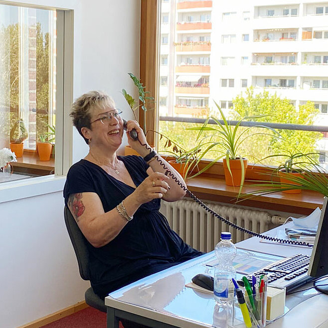 Die Mitarbeiterin von SOPHIA beantwortet einen Anruf glücklich. 