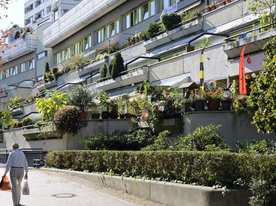 Ein Mann läuft mit Einkaufstaschen vor dem Gebäude entlang
