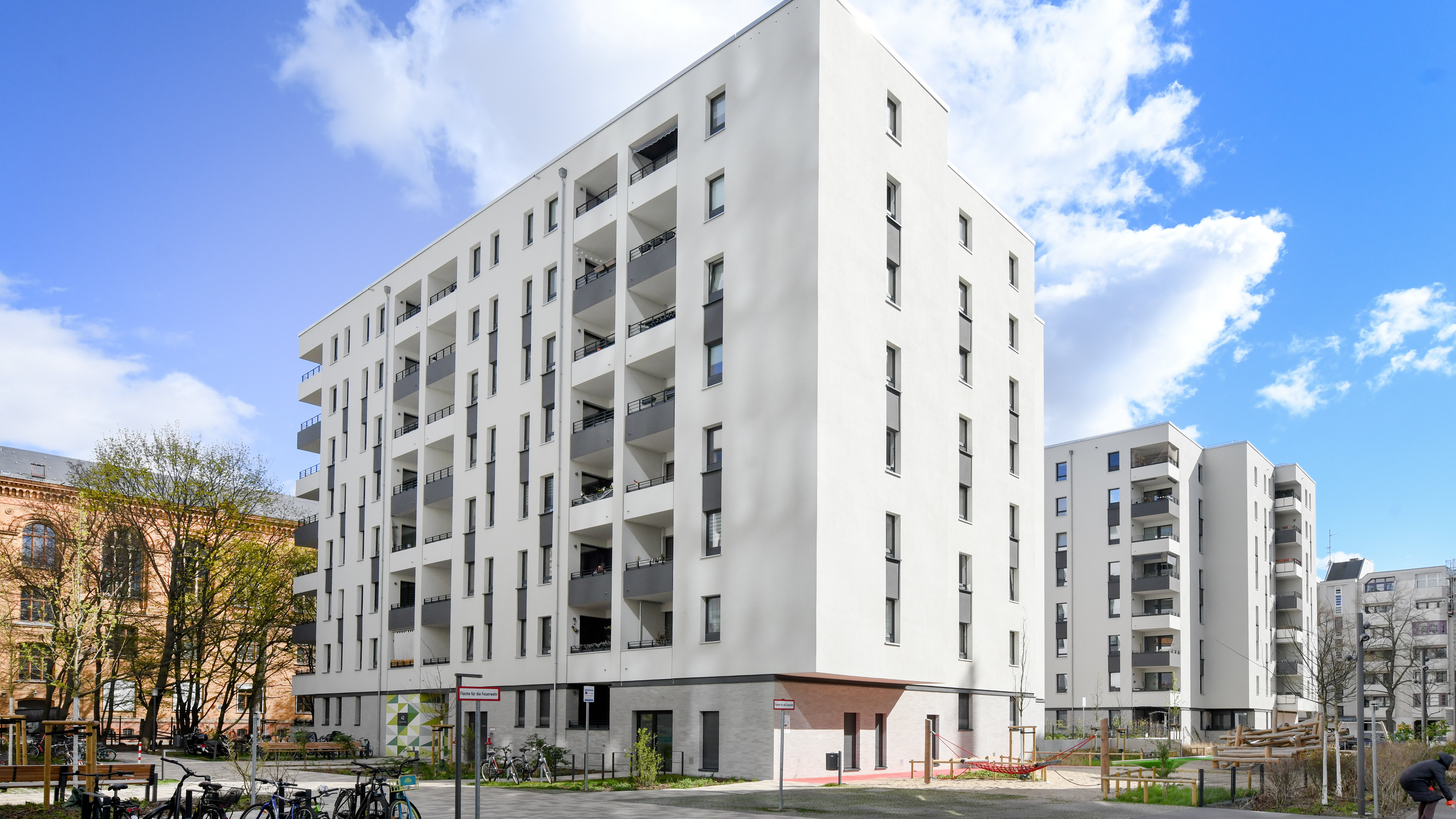 Modernes Mehrfamilienhaus mit Balkonen und Fahrrädern im Hof.