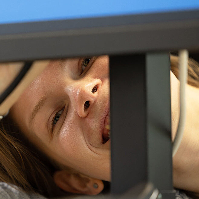 Frau guckt unter Bildschirm hervor und lacht