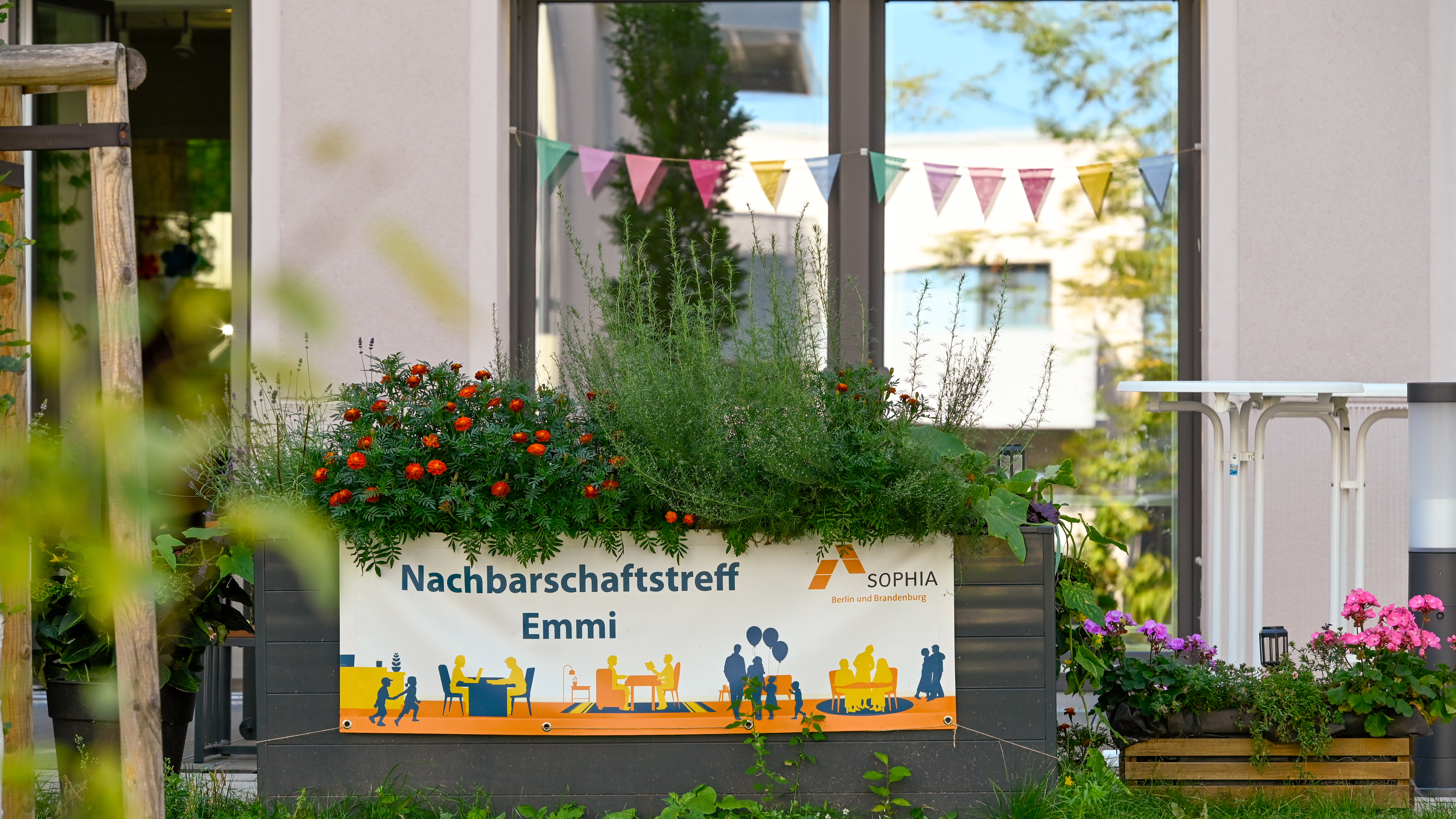 Hochbeet mit Blumen und Schild Nachbarschaftstreff Emmi.