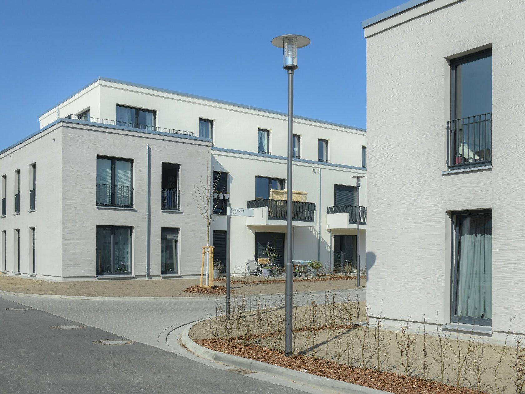 Außenansicht degewo-Neubau Bohnsdorfer Weg 127 bis 131 Knospengrund 27 bis 33 mit Straße und Straßenlaterne im Vordergrund.