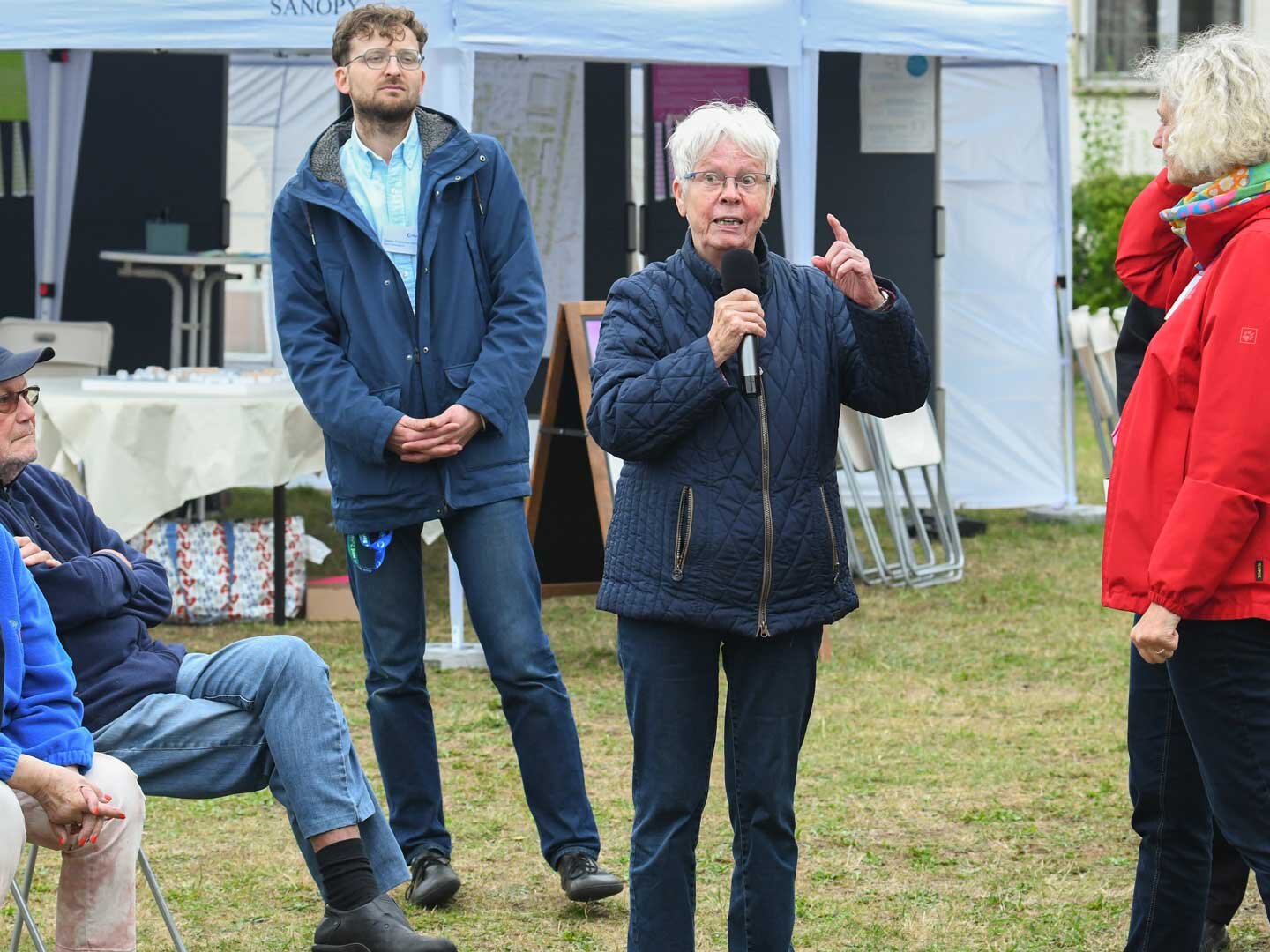 Mehrere Personen stehen um eine Frau im Kreis und hören ihr beim Reden zu.
