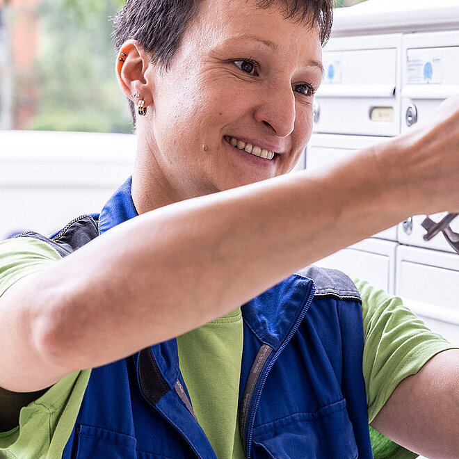 Hausmeisterin repariert Briefkastenschloss