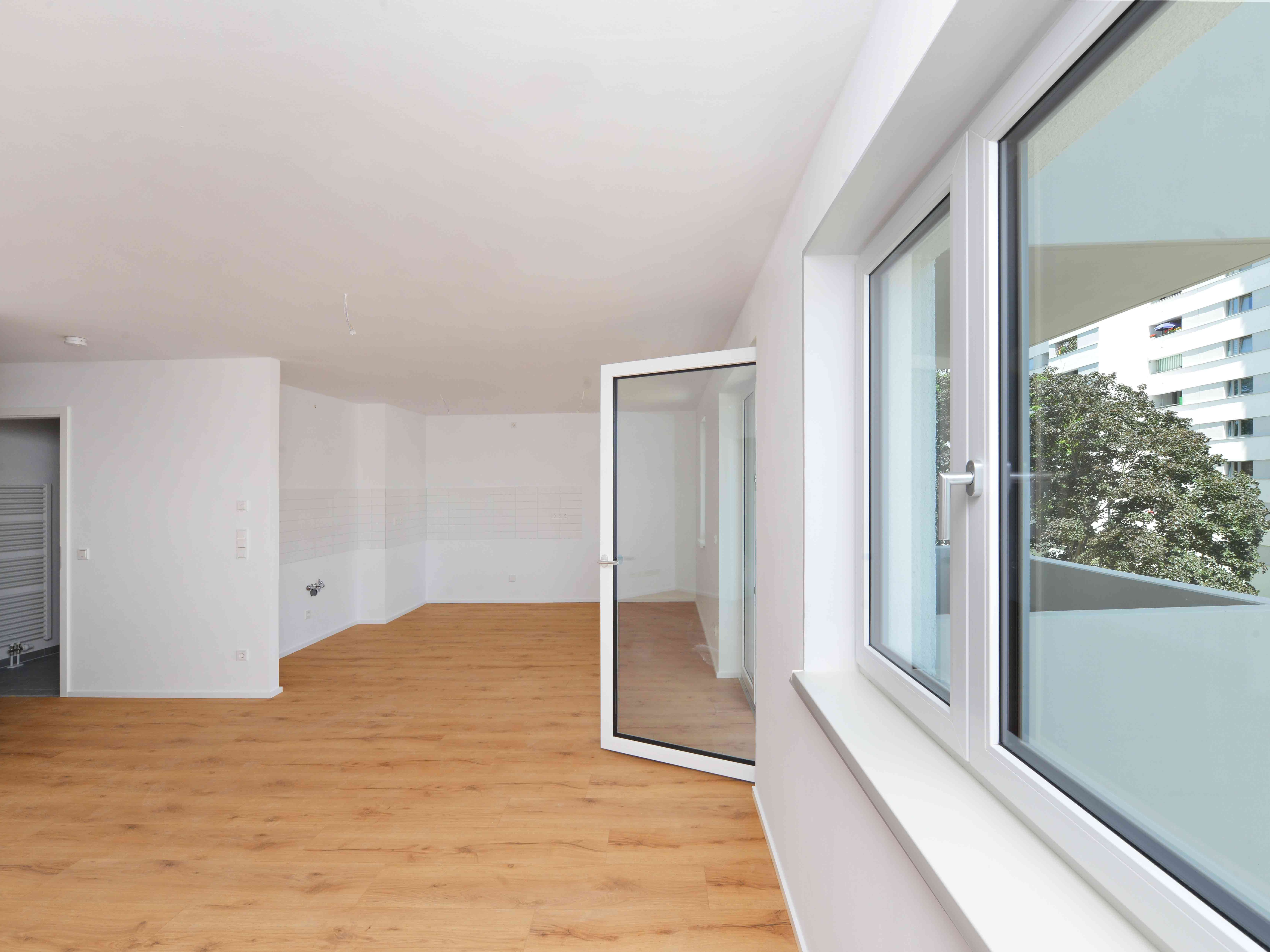 Innenansicht degewo-Neubau Agnes-Straub-Weg 22: leeres Zimmer mit geöffneter Balkontür.