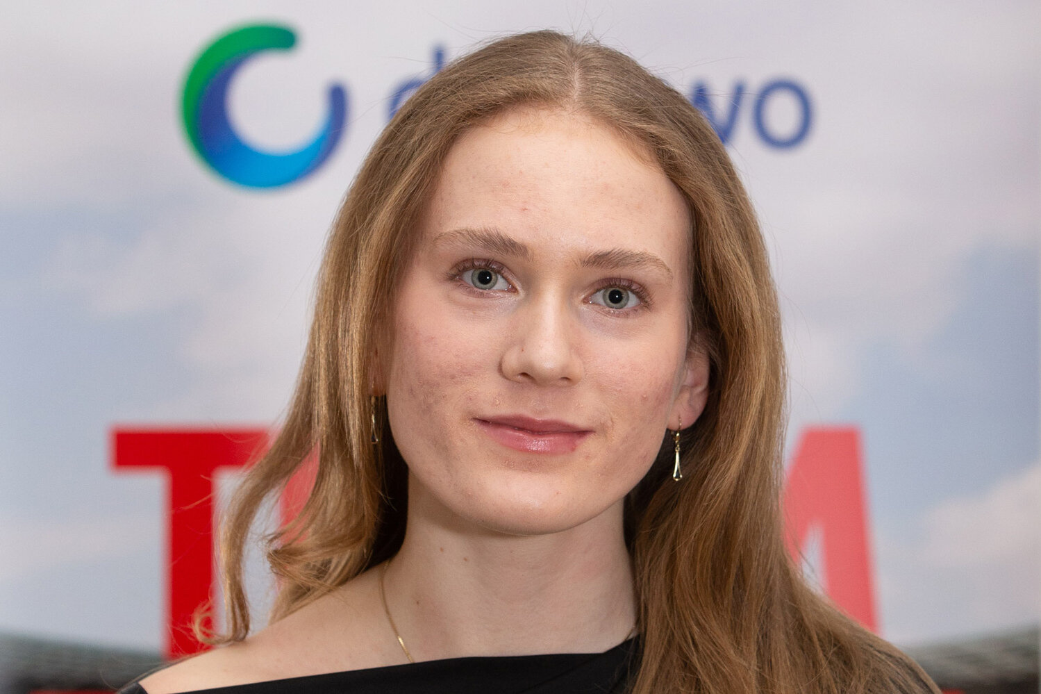 Nahaufnahme einer jungen Frau vor einer Sponsorenwand mit degewo-Logo. Sie lächelt leicht in die Kamera.