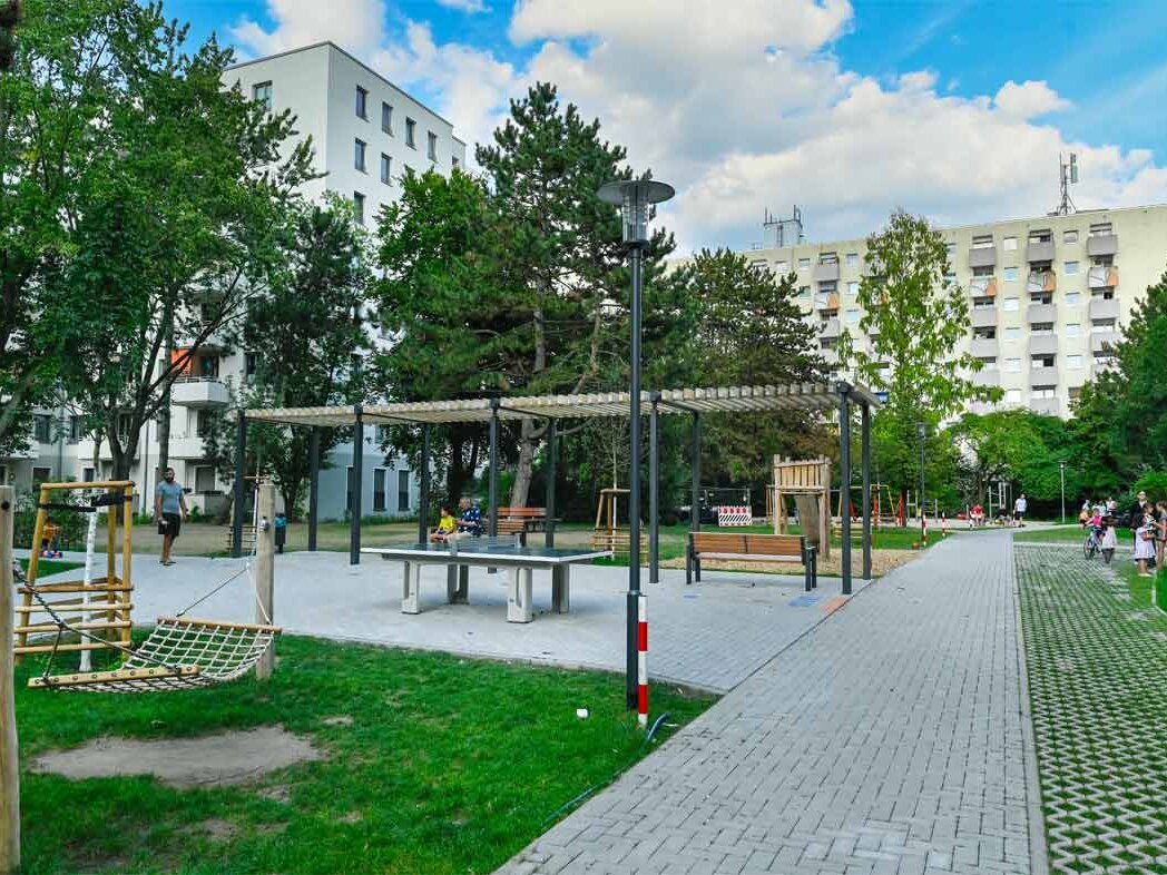 Außenansicht degewo-Neubau Borgenhagenweg 43 und 43A: Hofseite mit Spielplatz, rechts gepflasterter Weg im Vordergrund.