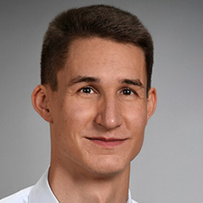 Portrait von Matthias Hundt. Ein junger Mann mit dunklen Haaren lächelt in die Kamera.