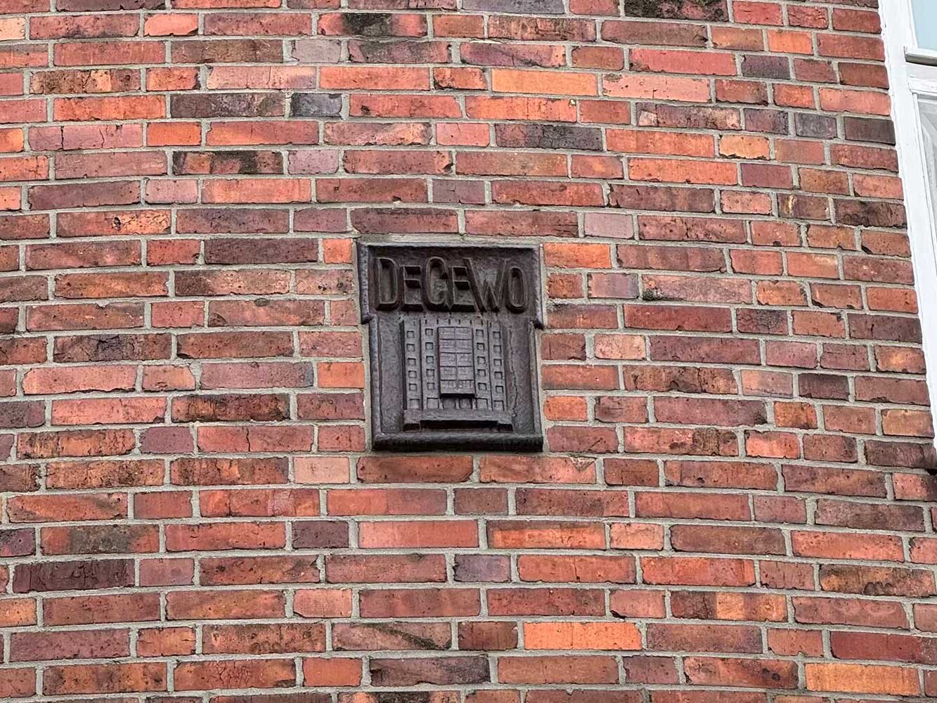 Ein Schmuckelement aus kupferfarbenen Material auf dem "DEGEWO" daraufsteht.