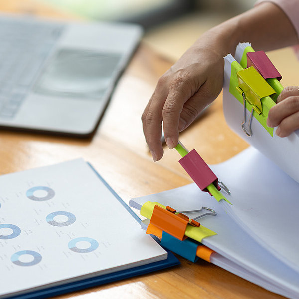 Hände einer Kauffrau beim Durchblättern ihrer Akten