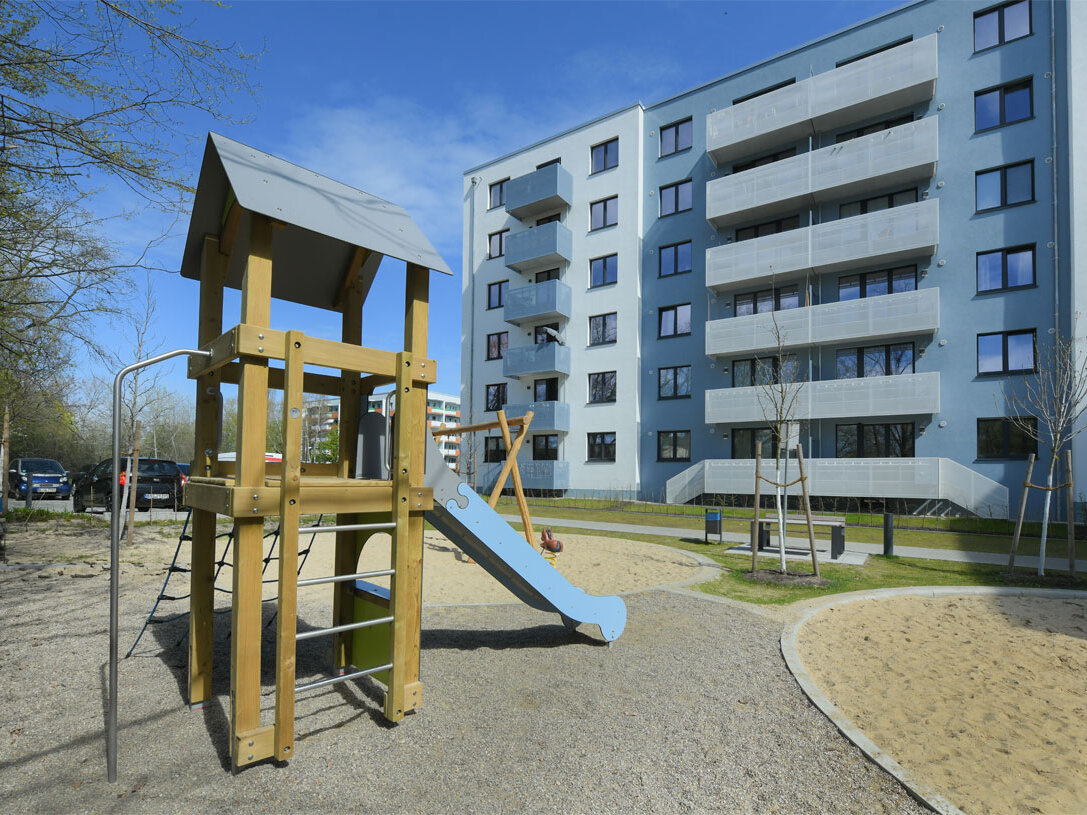 Außenansicht degewo-Neubau Pöhlbergstraße 9 Bärensteinstraße 5: Rückseite mit Spielplatz und neu gepflanzten Bäumen im Vordergrund.