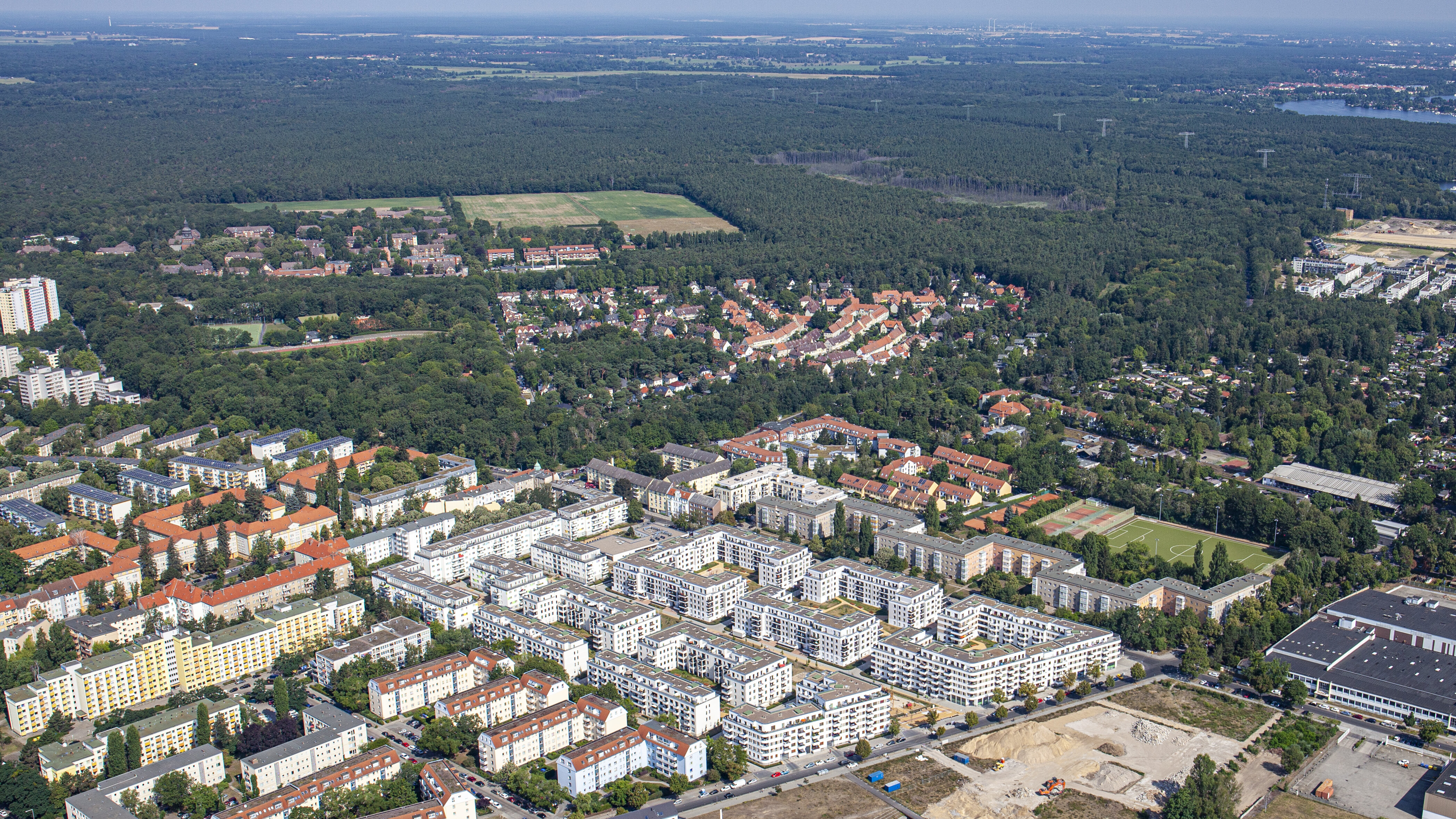Ein Luftbild zeigt die Pepitahöfe in Spandau aus der Vogelperspektive, bestehend aus mehreren Wohnblöcken in der Nähe eines großen Waldgebietes. Um die Pepitahöfe herum stehen weitere Wohnhäuser.