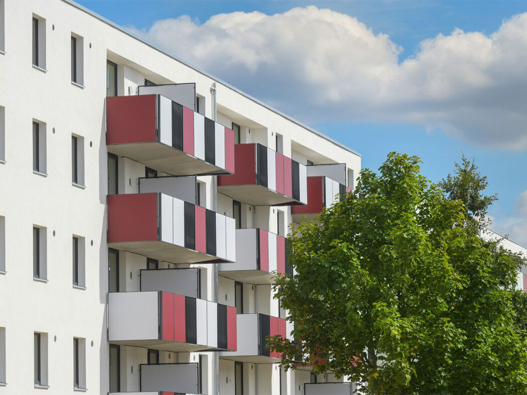 Außenansicht degewo-Neubau Schönefelder Chaussee 26 bis 38 Wegedornstraße 119 bis 123: Fassade mit Balkonen und Bäumen rechts.