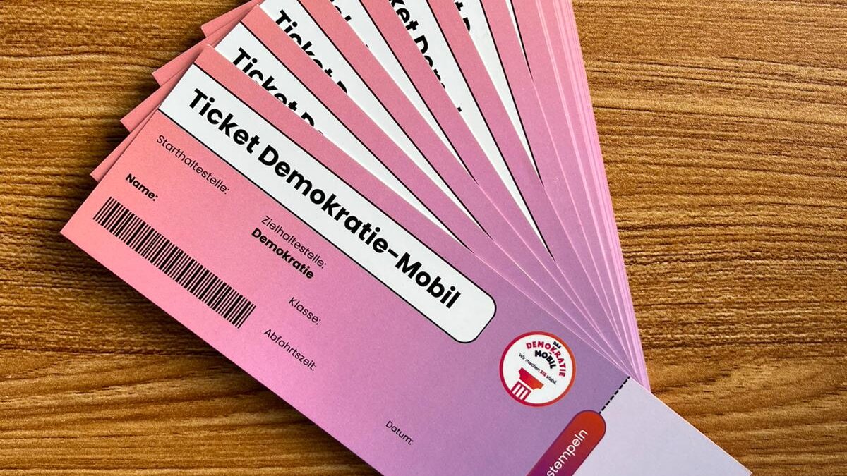 Mehrere rosafarbene Tickets mit der Aufschrift "Ticket Demokratie-Mobil" fächerförmig auf einem Holztisch ausgelegt.