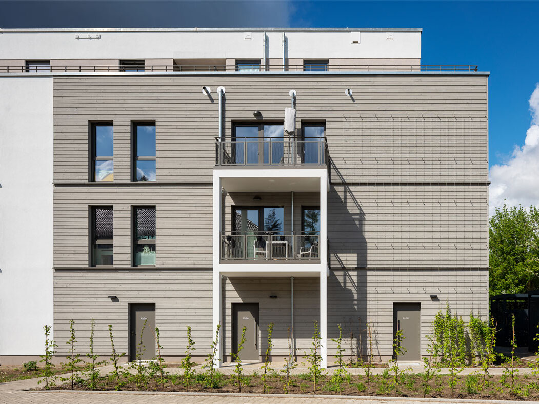 Außenansicht degewo-Neubau Stillerzeile 58 mit Balkonen und Beet vor dem Gebäude.