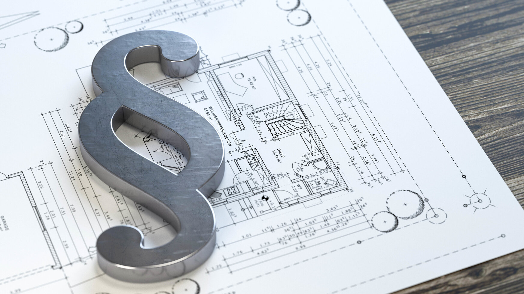 Metallisches Paragrafenzeichen (§) liegt auf einem ausgebreiteten Bauplan mit Grundrisszeichnungen, Maßangaben und technischen Details. Das Motiv verbindet die Themen Baurecht, Mietrecht oder rechtliche Rahmenbedingungen mit Planung und Immobilienwirtschaft.