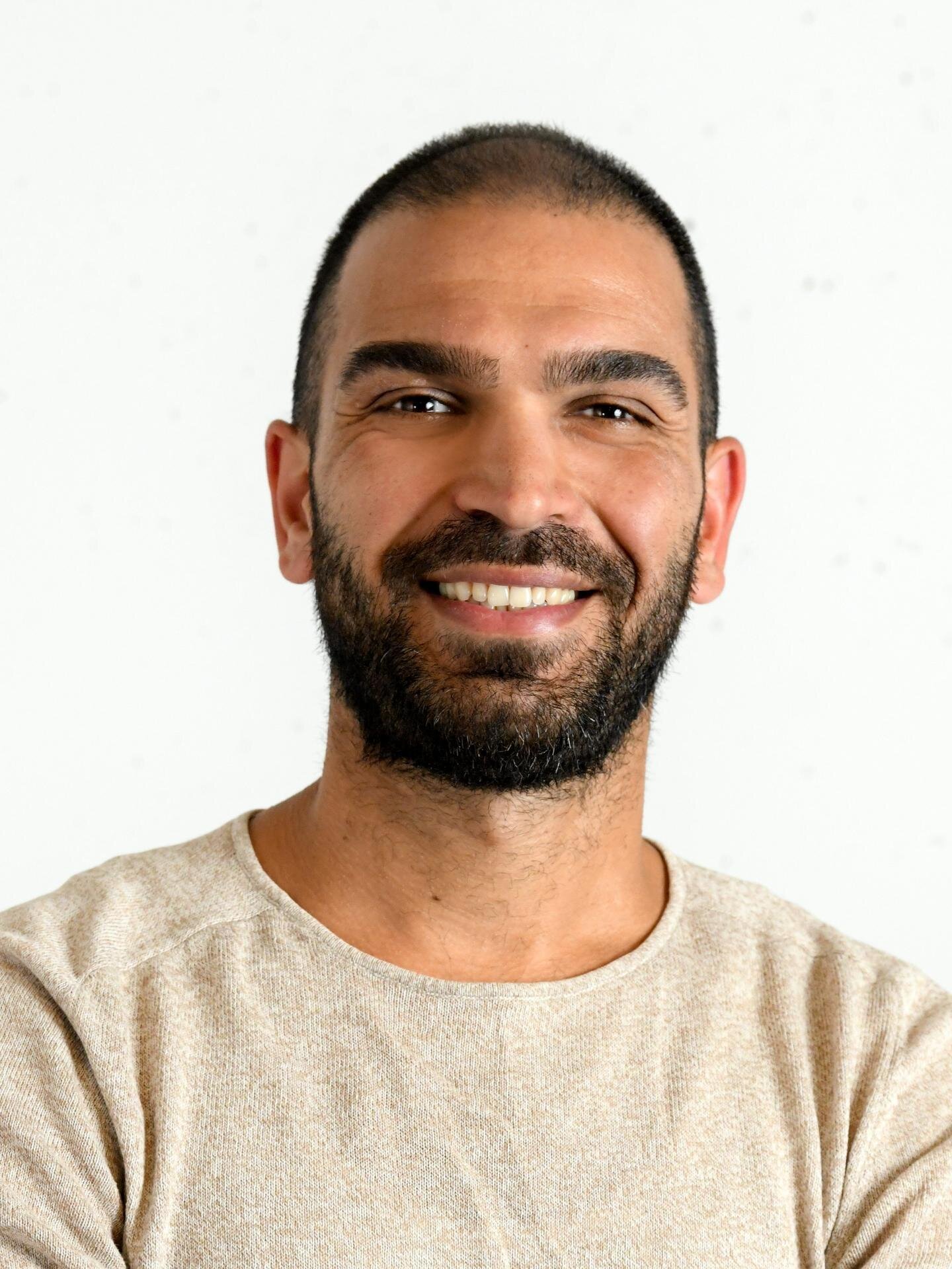 Porträt des Mieterbeiratsmitglieds Ismail Kaya in hellem Pullover vor neutralem Hintergrund