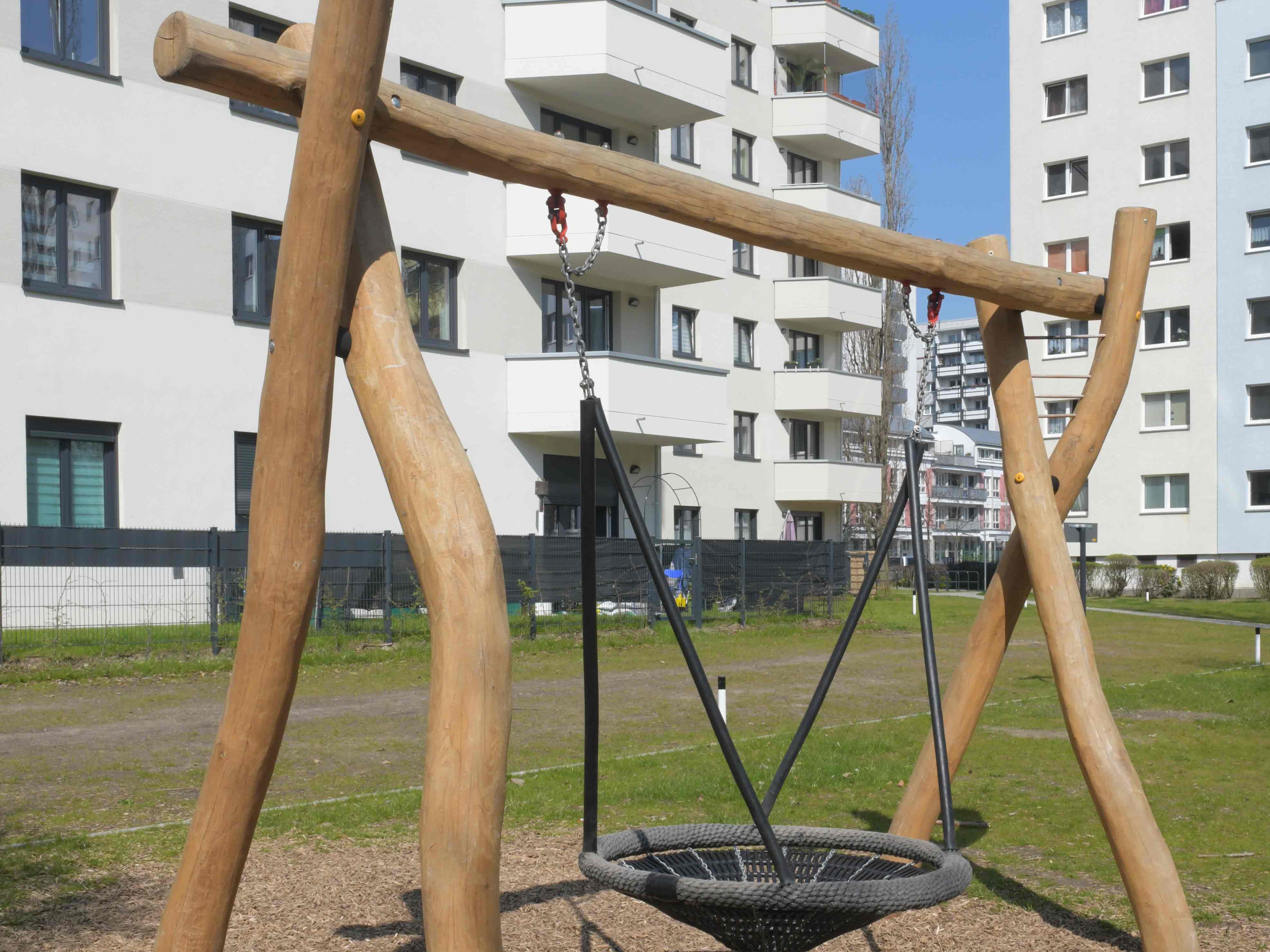 Außenansicht degewo-Neubau Wuhlestraße 2 bis 8 mit Rasenfläche und Nestschaukel im Vordergrund.