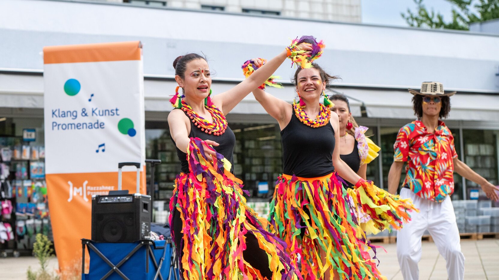 Drei Frauen und ein Mann in Kostümen tanzen.
