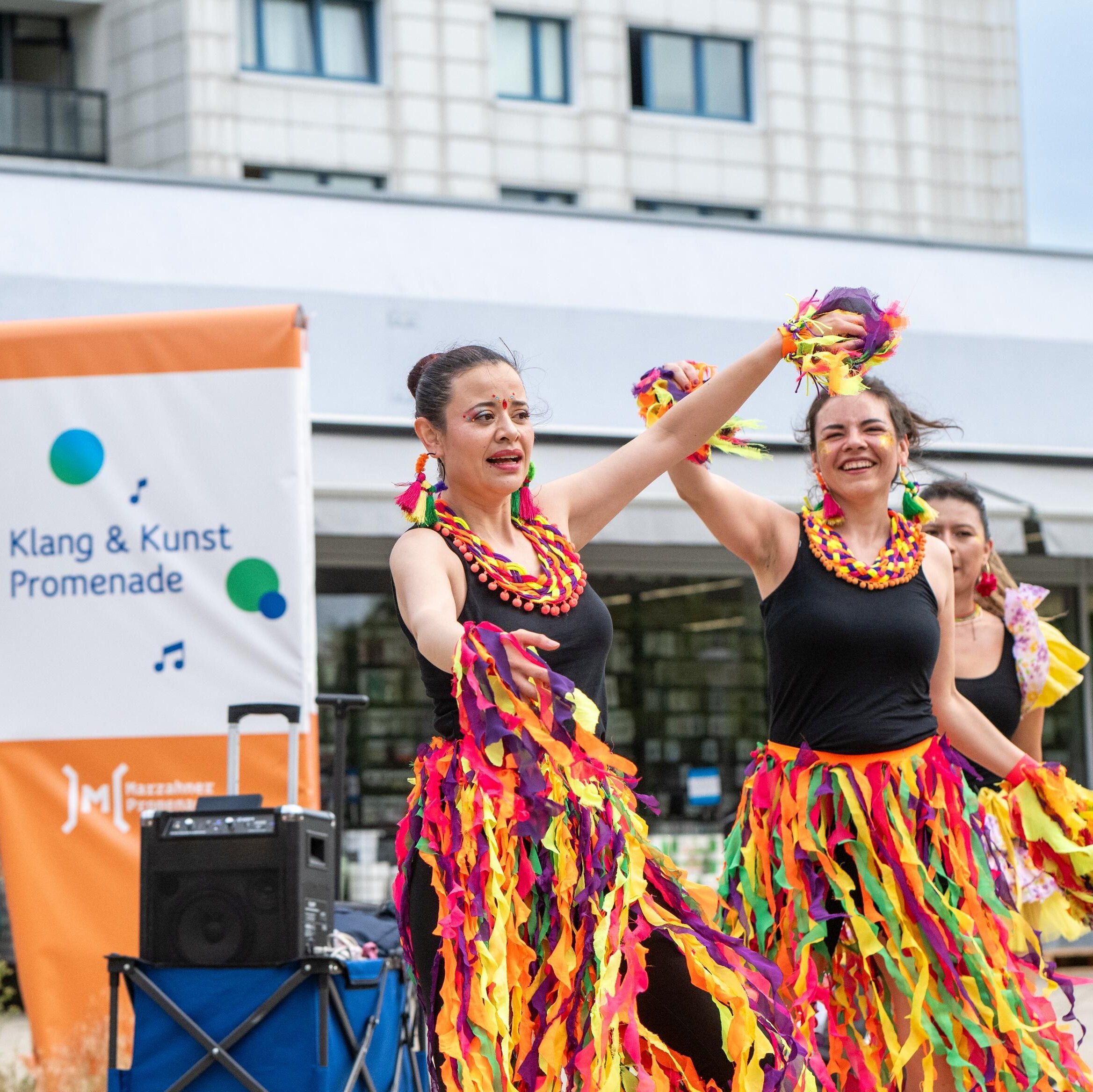Drei Frauen und ein Mann in Kostümen tanzen.