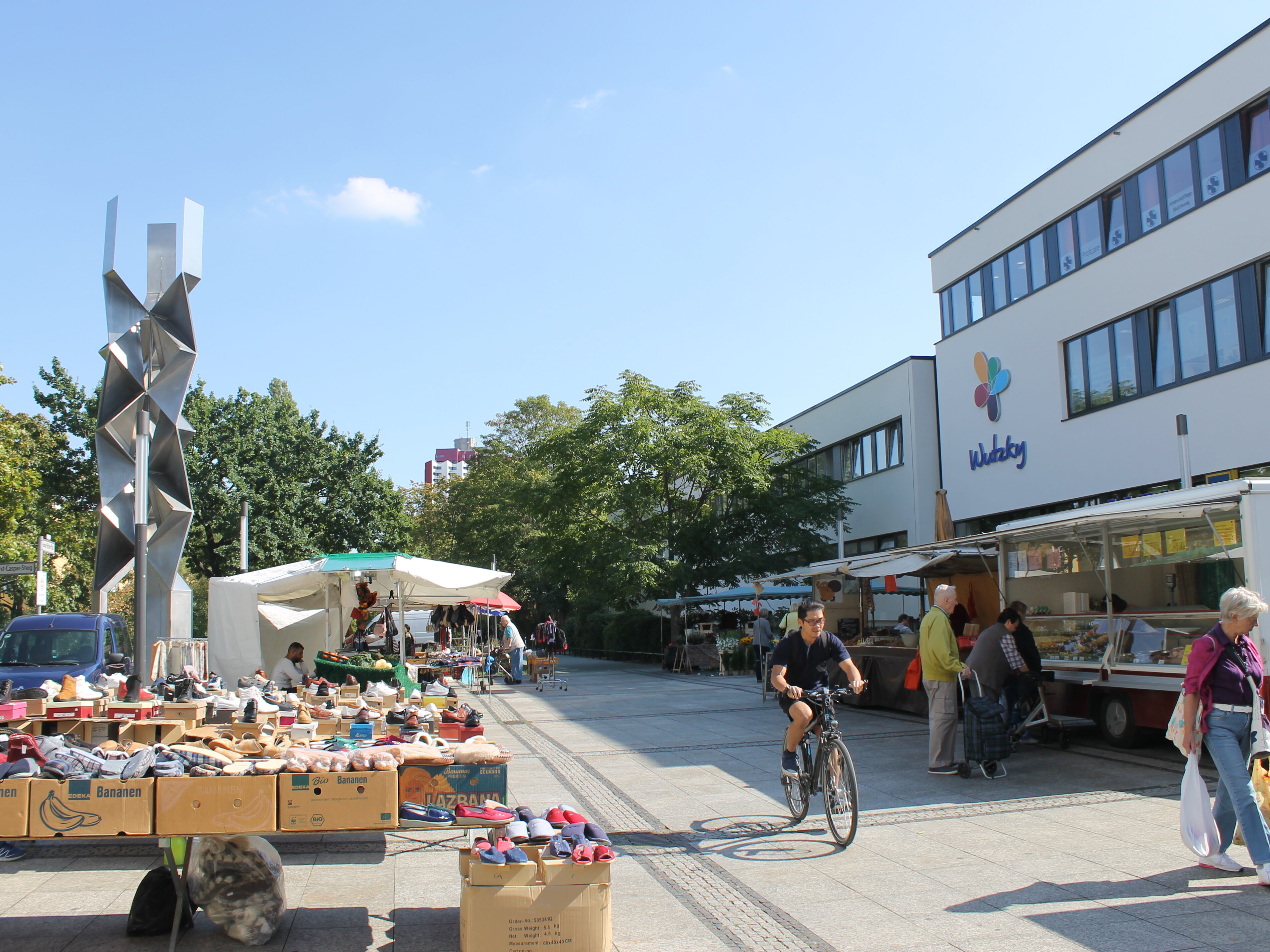 Ein Platz vor einem weißen Gebäude mit Ständen und Menschen