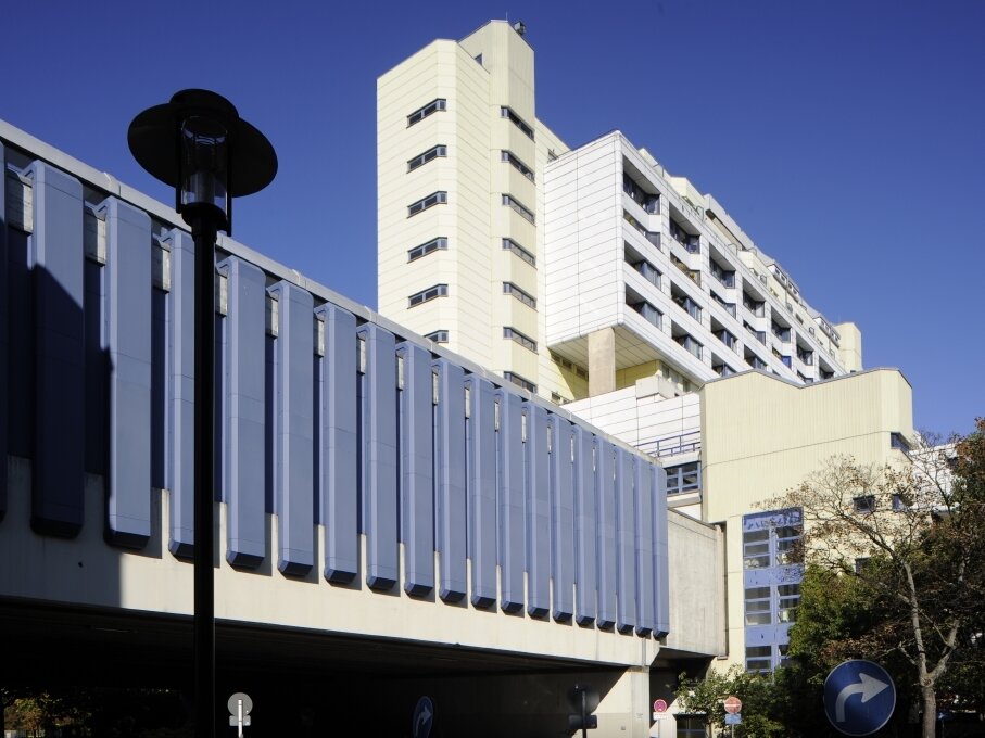 Ein weißes Hochhaus von schräg unten mit Fußgängertunnel