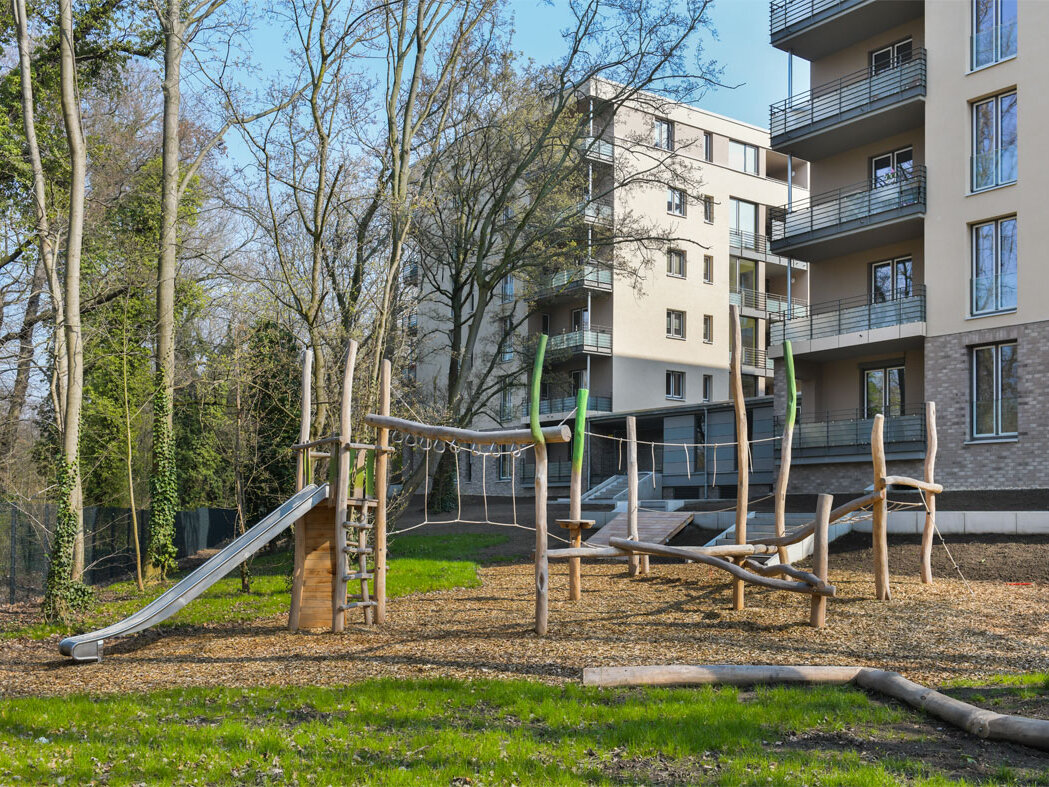 Außenansicht degewo-Neubau Pulsstraße 13 und 15: Hofseite mit Spielplatz und Rasenfläche im Vordergrund.