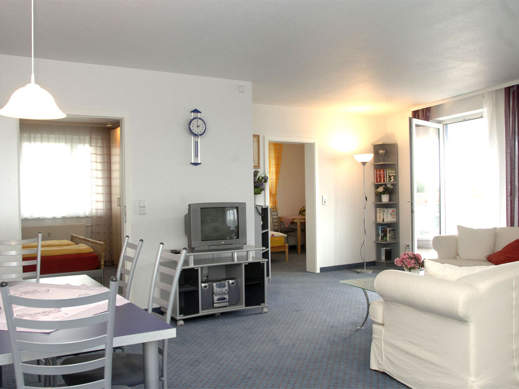 Innenraum mit Sofa, Esstisch und Fernseher.