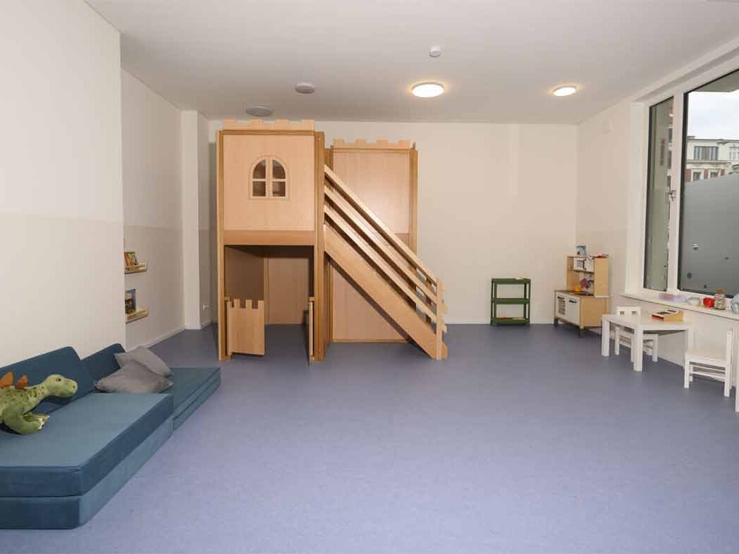 Innenansicht degewo-Neubau Gotenburger Straße 2: beleuchtetes Kita-Spielzimmer mit Rutsche und Matten.