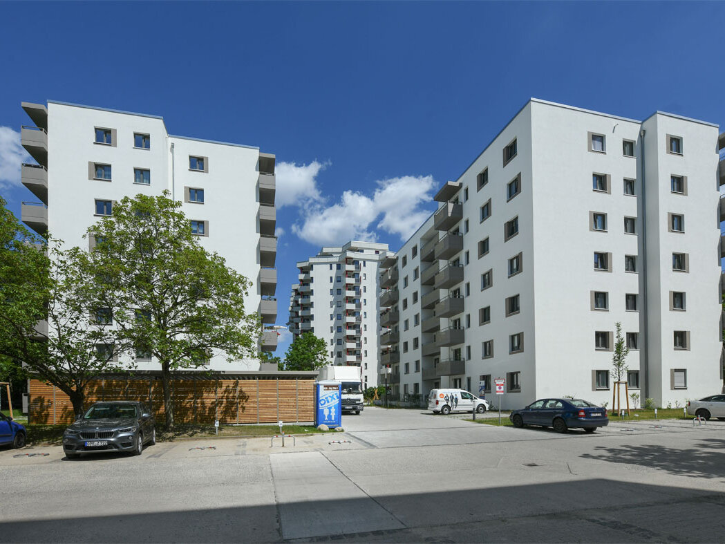Außenansicht degewo-Neubau Theodor-Loos-Weg 15 und 15 A mit Parkplatz im Vordergrund.