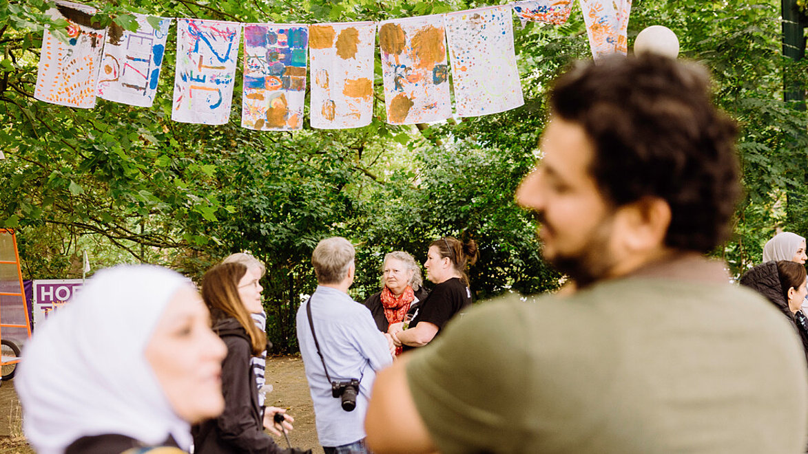 Einige Menschen stehen auf dem Apfelsinenplatz in Gropiusstadt und unterhalten sich