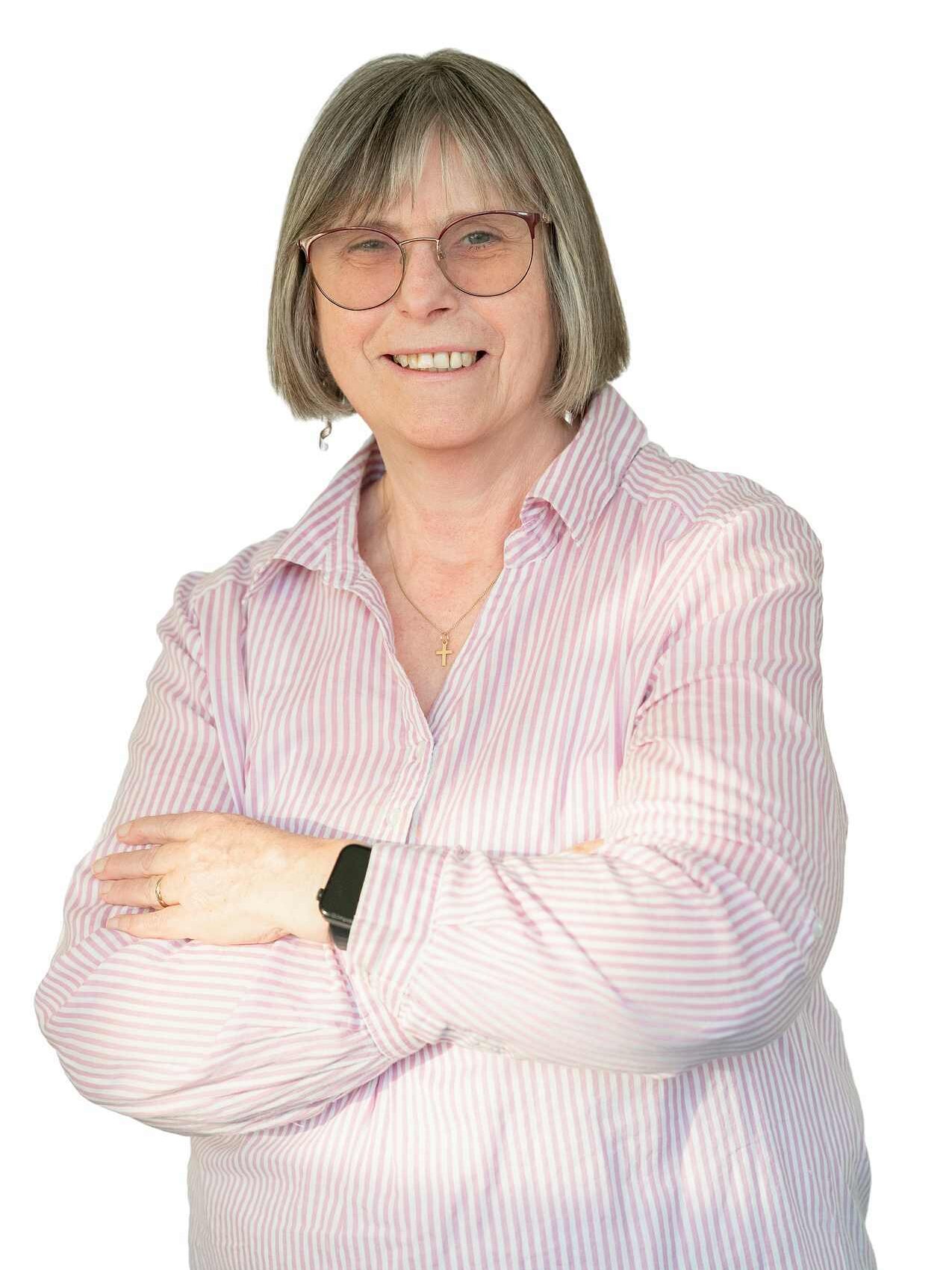 Portrait der Mieterbeirätin Eva-Maria Söffky-Appiah. Sie trägt eine rosafarbene Bluse, hat die Arme vor der Brust überkreuzt und lächelt in die Kamera.