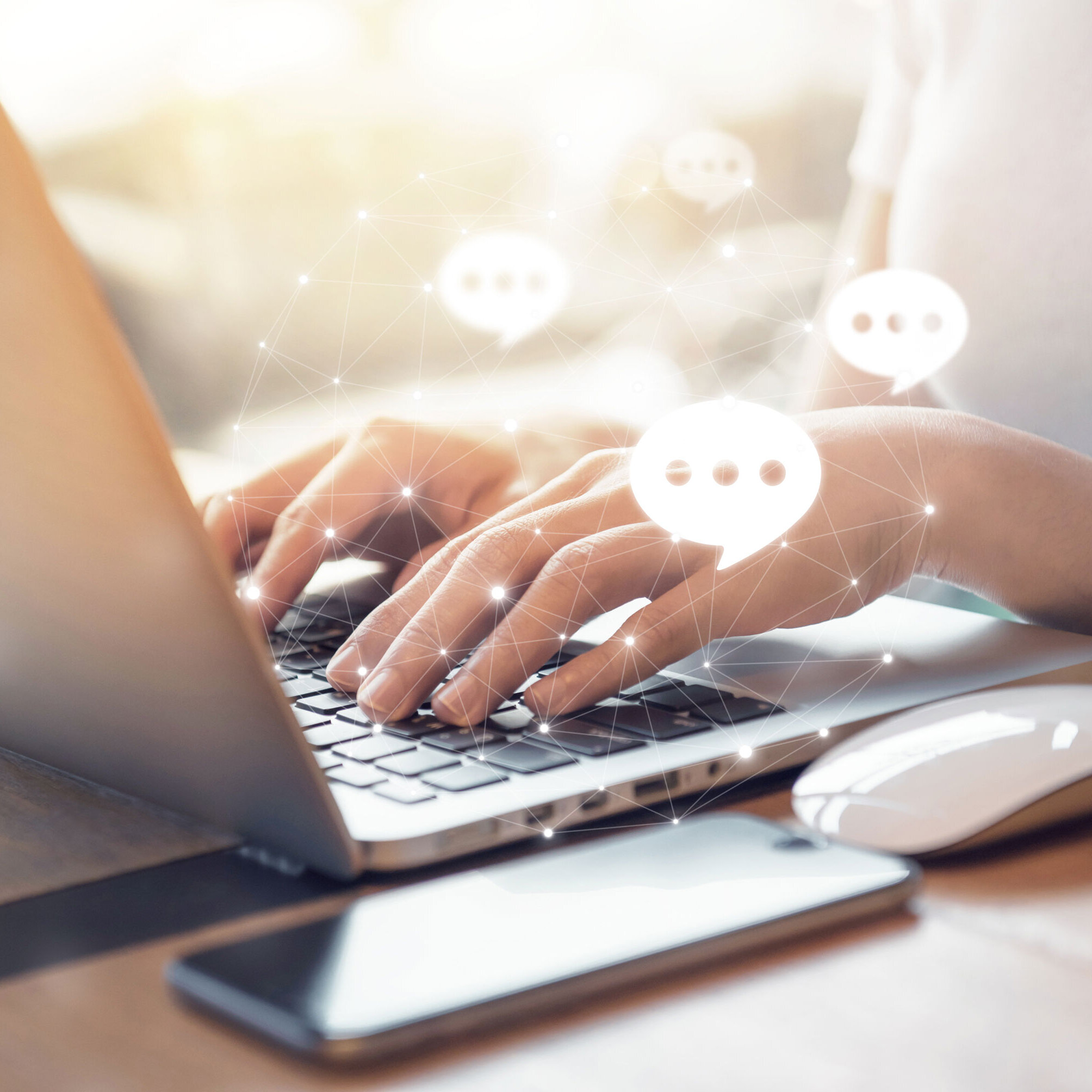 Hände tippen auf einer Laptop-Tastatur, daneben Smartphone und Maus; eingeblendete Chat-Symbole stehen für digitalen Kundenservice und Online-Kommunikation.