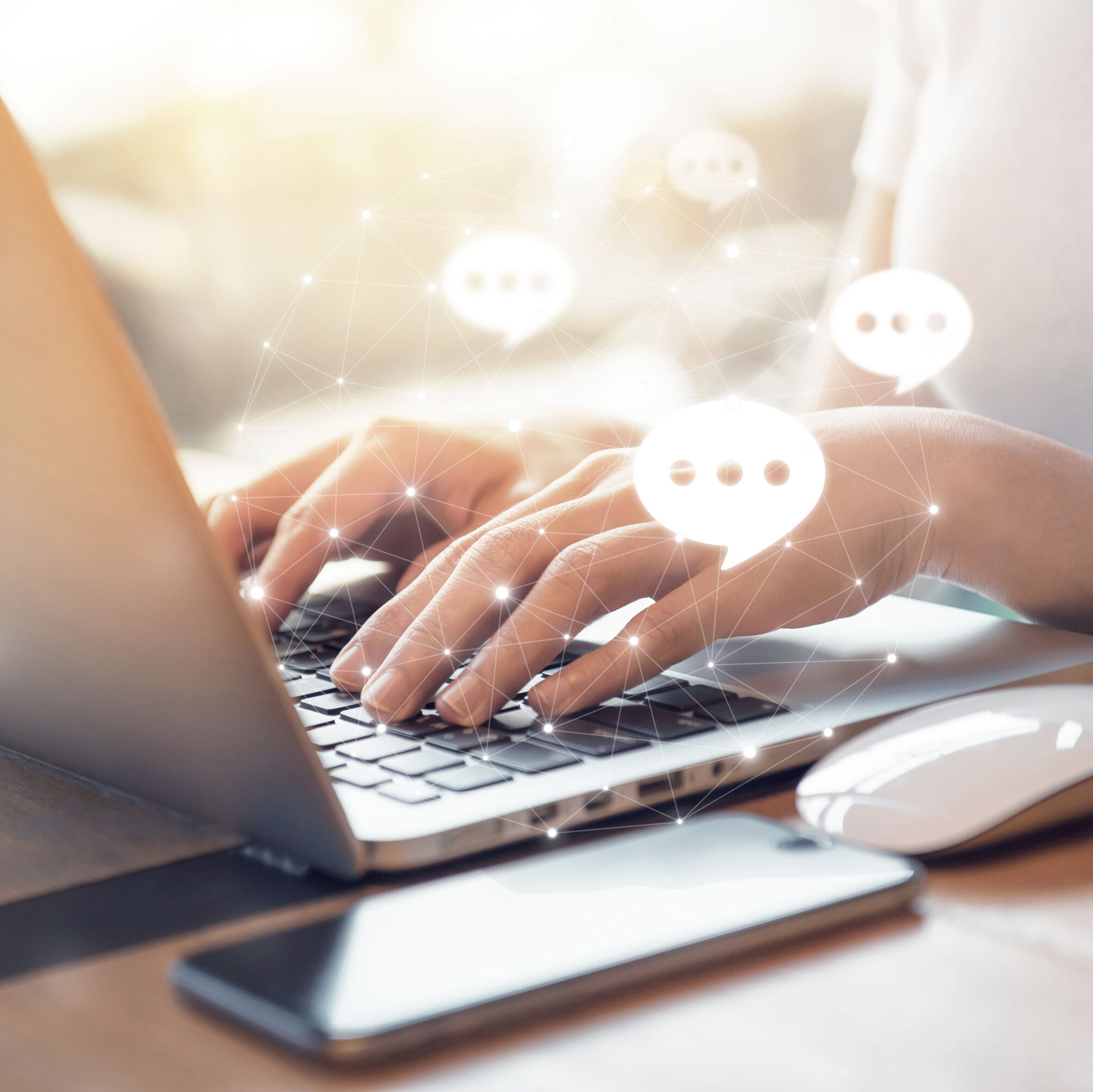 Hände tippen auf einer Laptop-Tastatur, daneben Smartphone und Maus; eingeblendete Chat-Symbole stehen für digitalen Kundenservice und Online-Kommunikation.