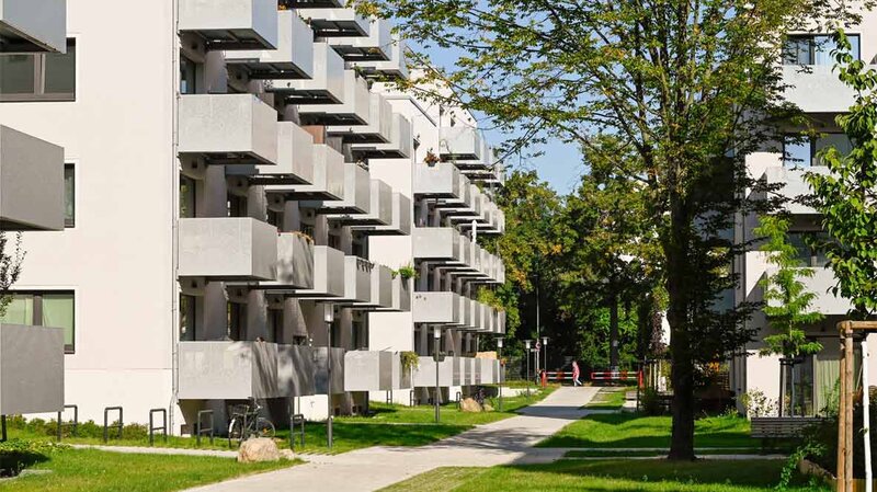 Außenansicht degewo-Neubau Malteserstraße 62: Rückseite mit Weg, Rasenflächen und Baum rechts im Vordergrund.