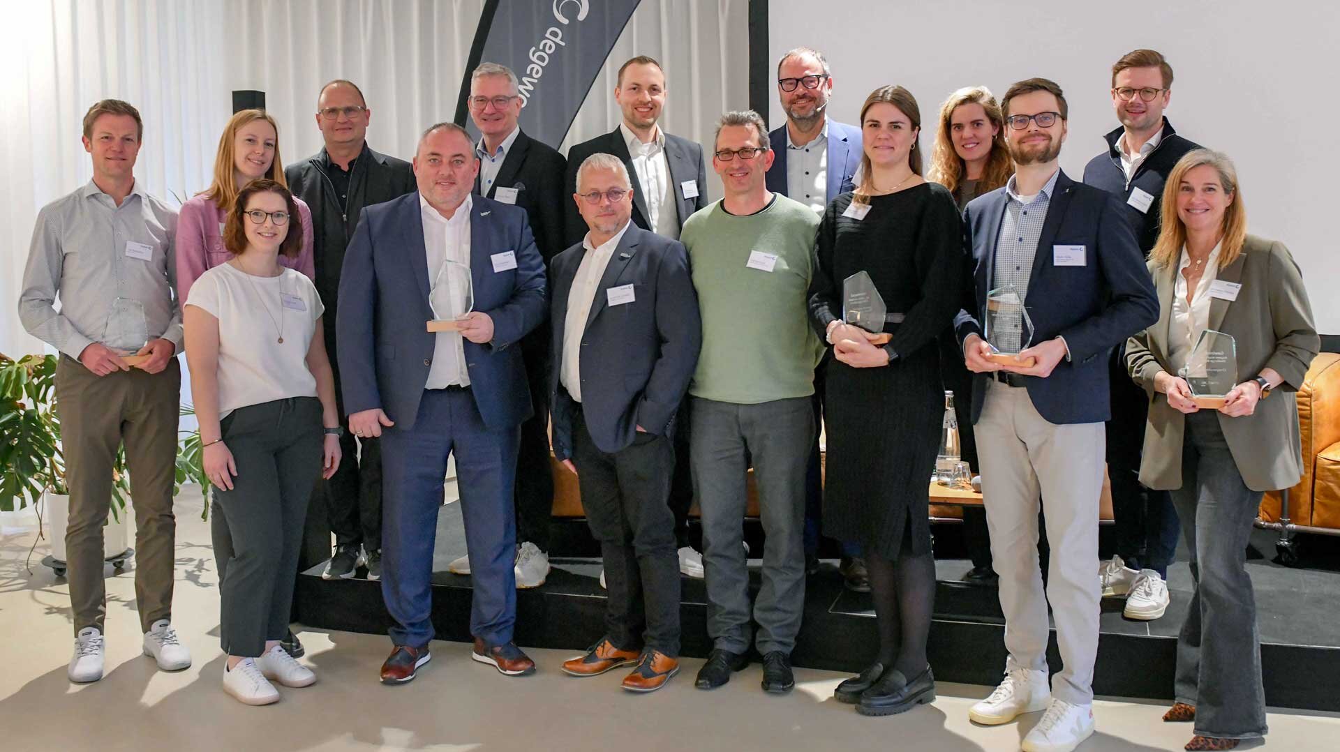 Gruppenaufnahme degewo Vorstand, netzwerk und aller Gewinner. Sie lachen in die Kamera und halten ihre Preise. 