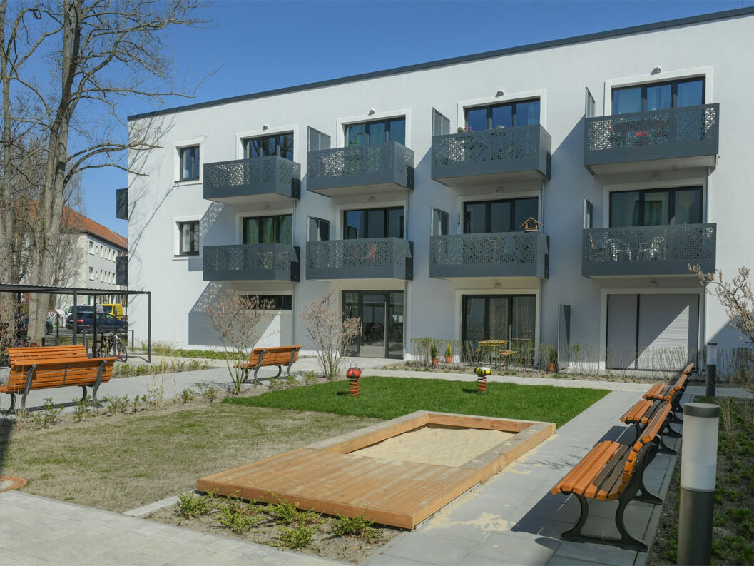Außenansicht degewo-Neubau Rudower Straße 47 bis 51: Hofseite mit Spielplatz und Sitzbänken.