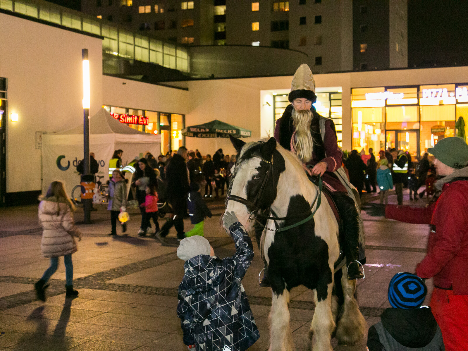 Ein Pferd mit kostümiertem Reiter und Menschen drum herum mit Laternen