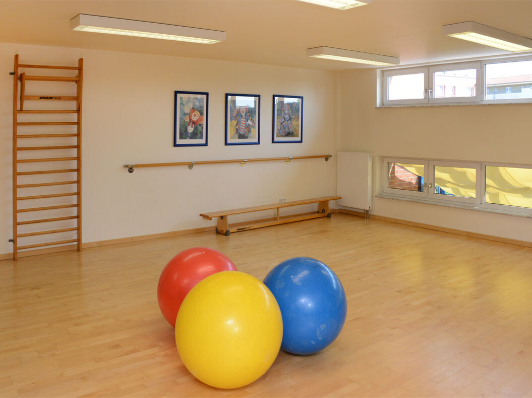 Innenraum einer Gymnastikhalle mit bunten großen Bällen.