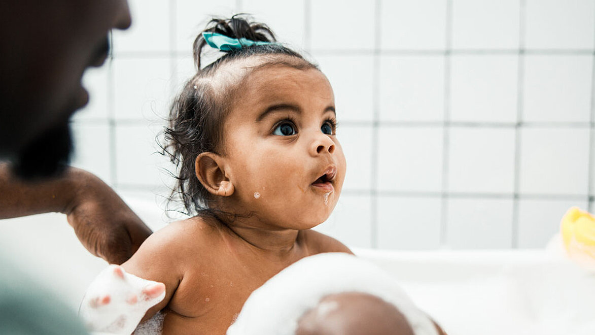 Kleinkind sitzt in einer Badewanne mit einer gelben Gummiente