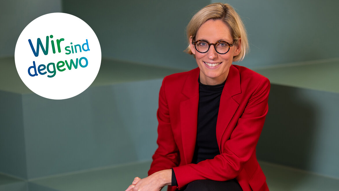 Eine Frau in einem roten Blazer sitzt lächelnd auf einer Treppe während ein degewo Logo mit der Aufschrift Wir sind degewo eingeblendet ist.