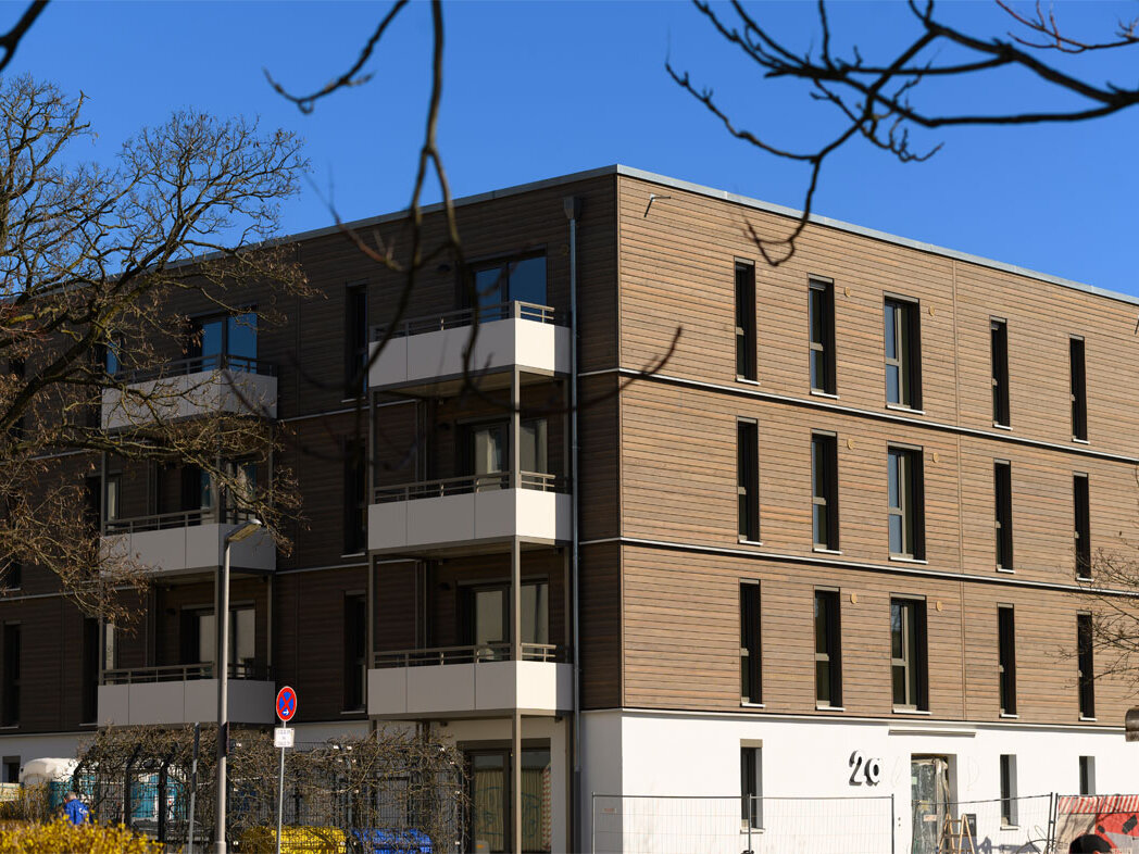 Außenansicht degewo-Neubau Am Omnibushof 2a mit unbeblätterten Baumzweigen oben im Vordergrund.