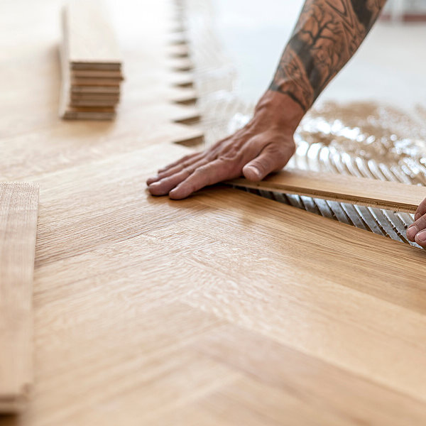Hände eines Bodenlegers bei der Arbeit